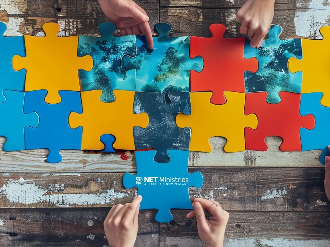 people assembling a puzzle on a wooden table