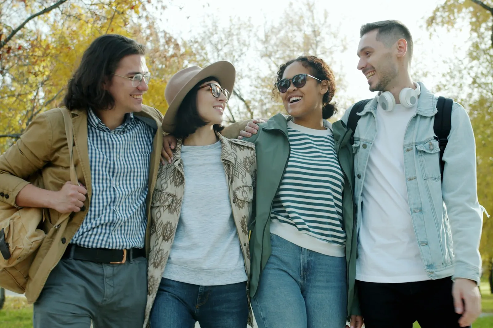 Four young people walking together through a park