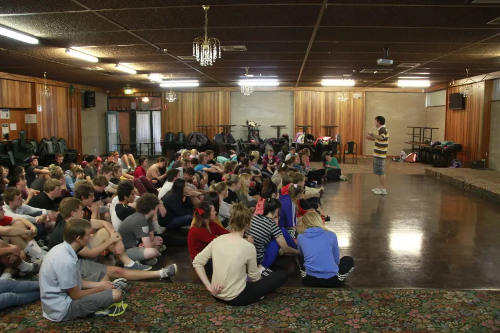 A speaker with young people seated on a hall floor