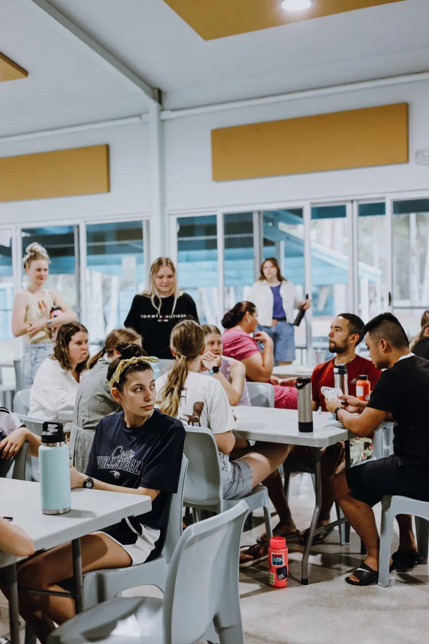 Small groups talking around tables in a bright hall