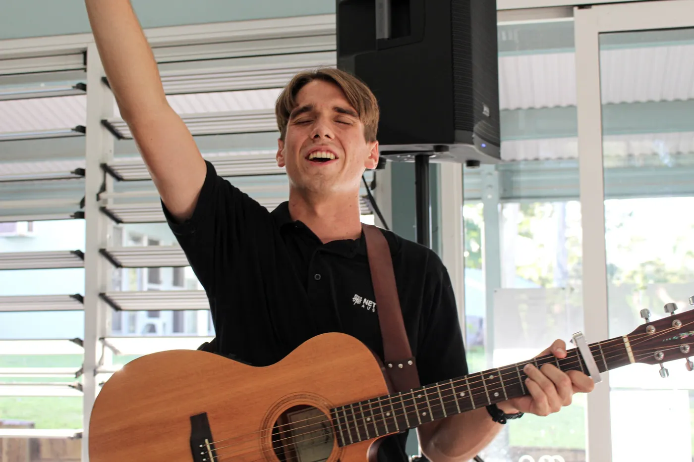 A young man playing guitar with one hand raised