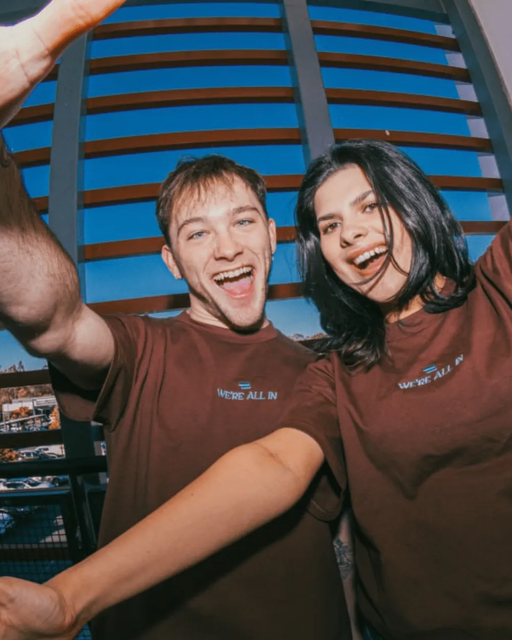 Two young people in brown shirts smiling at the camera