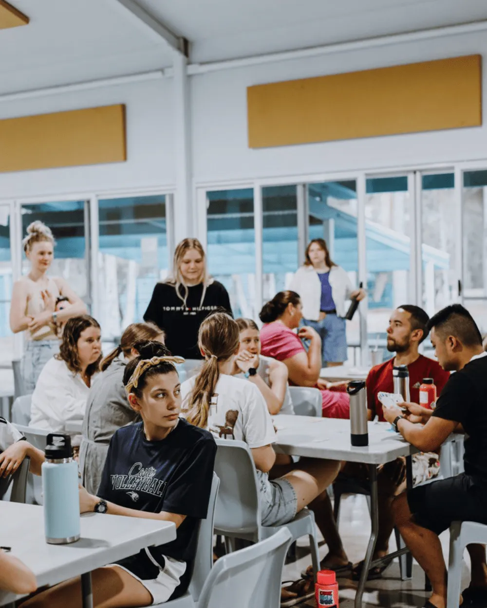 Small groups talking around tables in a bright hall