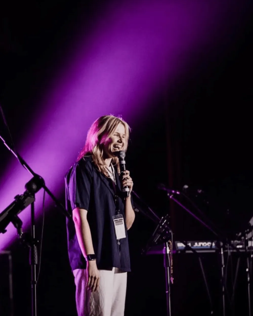 A woman speaking on a stage in purple light