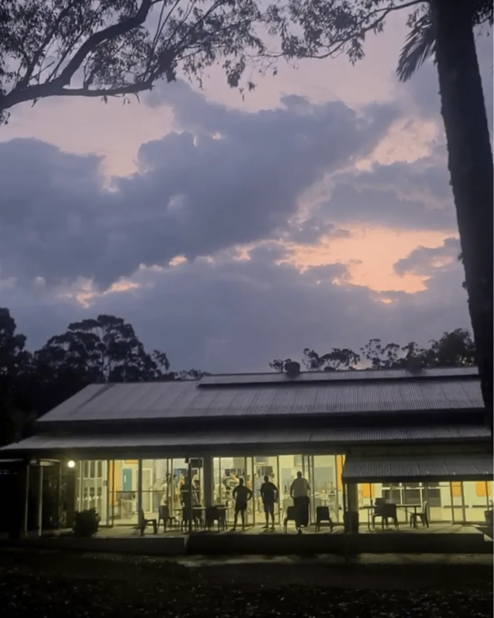 A lit hall at dusk, with people visible through the windows
