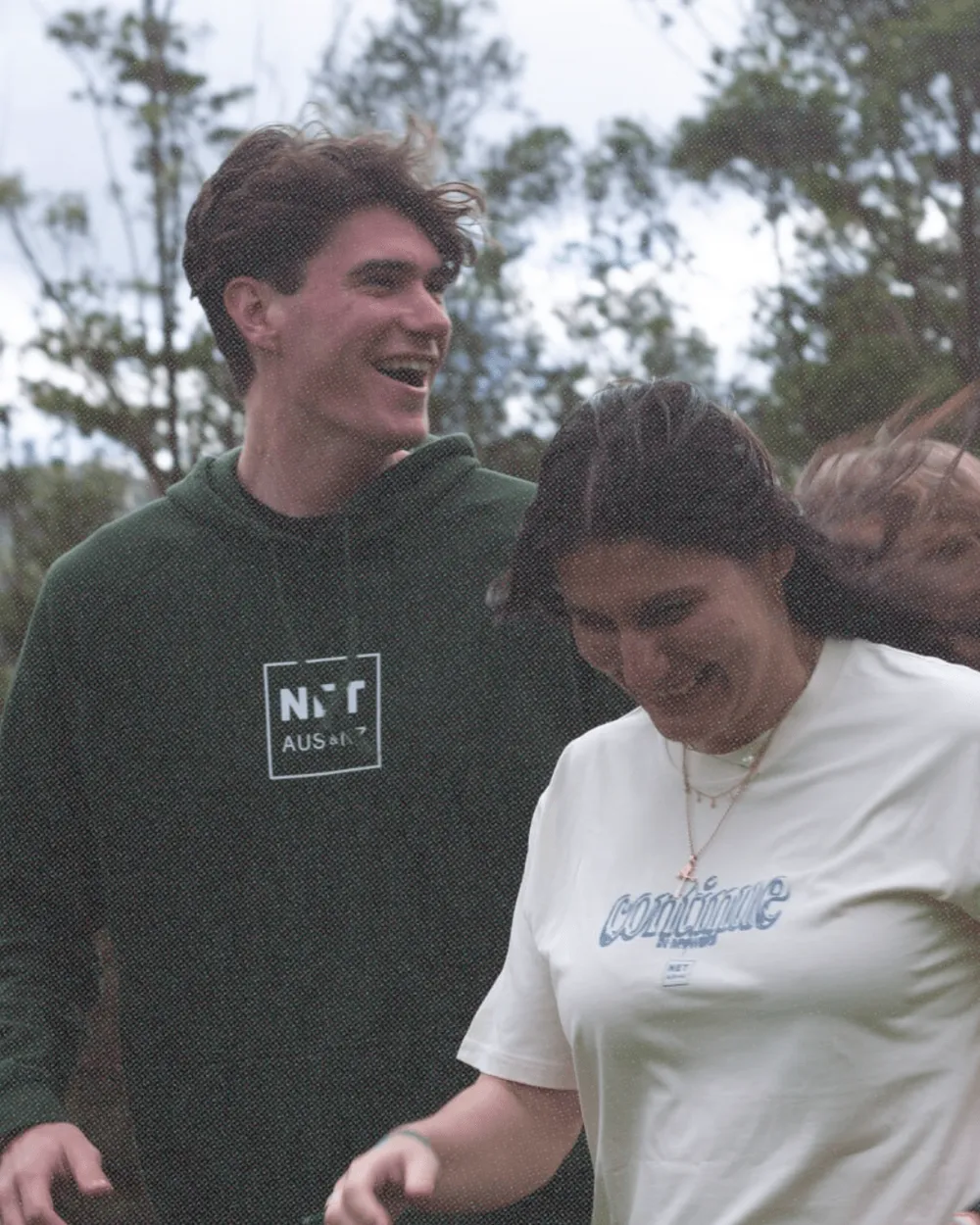 Two young people walking and laughing among the trees